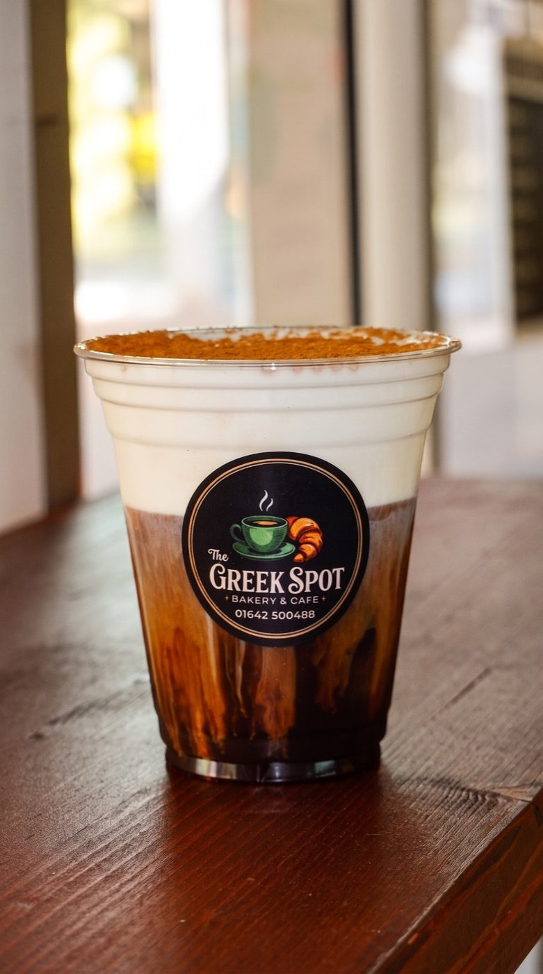 An iced Greek coffee served in a branded The Greek Spot cup