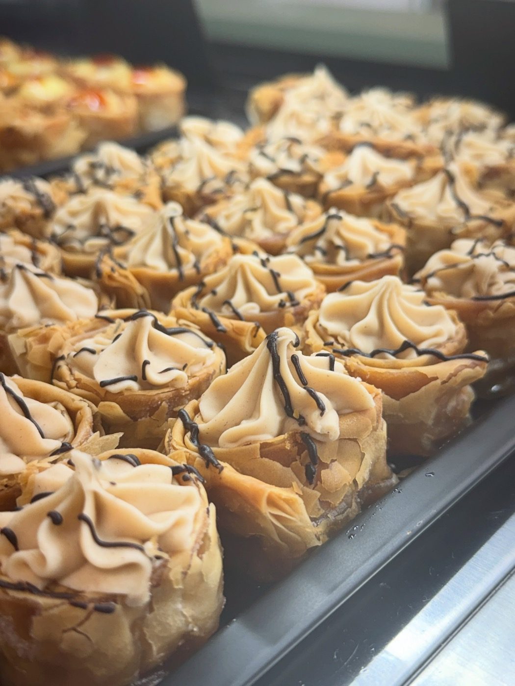 Tray of mini filo baklava cups topped with cream on the counter at The Greek Spot in Middlesbrough.
